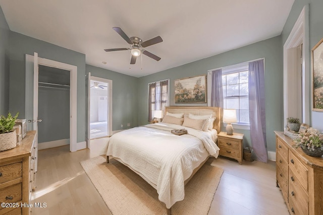 bedroom with ceiling fan, light hardwood / wood-style floors, and a closet