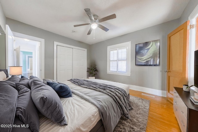 bedroom with ceiling fan, light wood-type flooring, and a closet