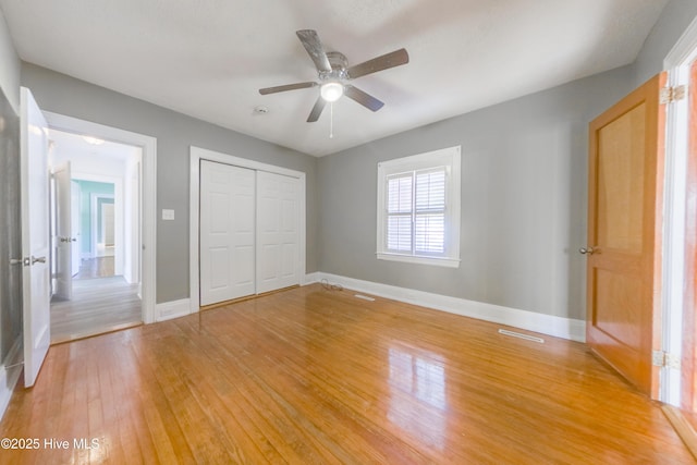 unfurnished bedroom featuring wood-type flooring, ceiling fan, and a closet