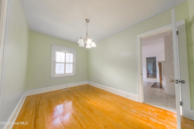 spare room featuring a chandelier and hardwood / wood-style floors