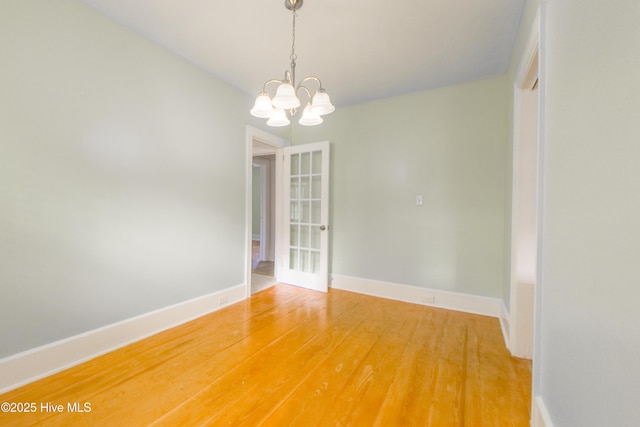 unfurnished room featuring wood-type flooring and a chandelier