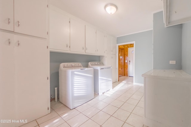 laundry area featuring washer and dryer, cabinets, and light tile patterned flooring