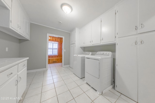 clothes washing area featuring cabinets, crown molding, light tile patterned floors, and washing machine and clothes dryer