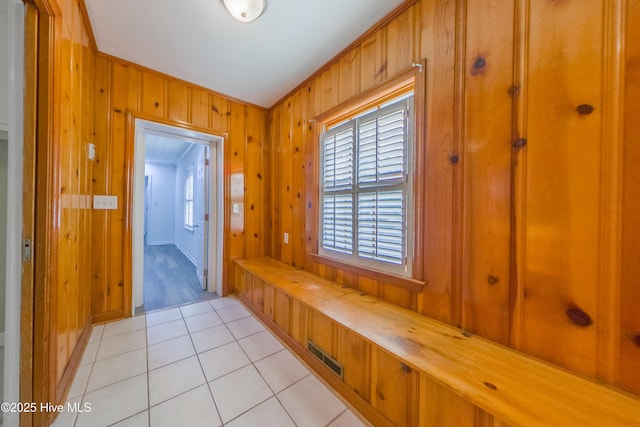 mudroom with light tile patterned floors and wooden walls