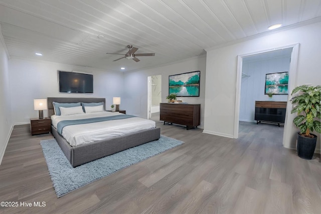 bedroom with ensuite bath, a walk in closet, ceiling fan, crown molding, and light wood-type flooring