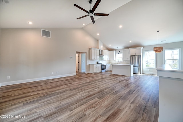 unfurnished living room featuring ceiling fan, high vaulted ceiling, sink, and light hardwood / wood-style floors