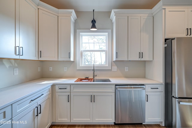 kitchen with light countertops, white cabinetry, stainless steel appliances, and a sink