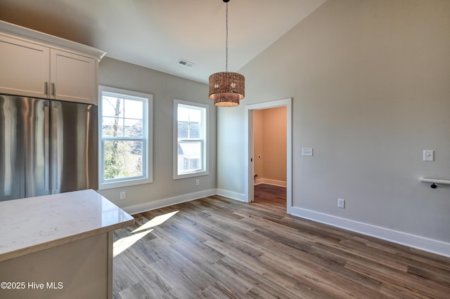 unfurnished dining area with hardwood / wood-style flooring and high vaulted ceiling