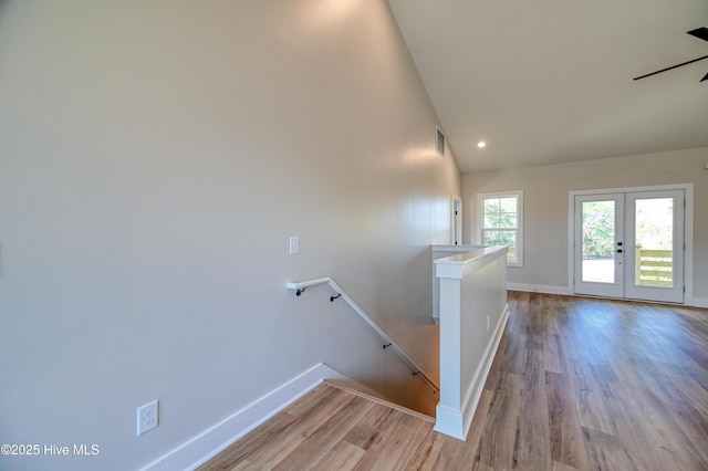 stairway featuring high vaulted ceiling, baseboards, wood finished floors, and visible vents