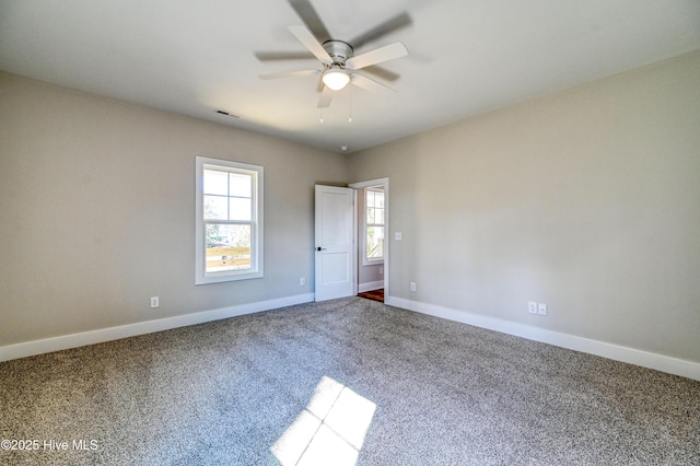 carpeted empty room with ceiling fan, baseboards, and visible vents