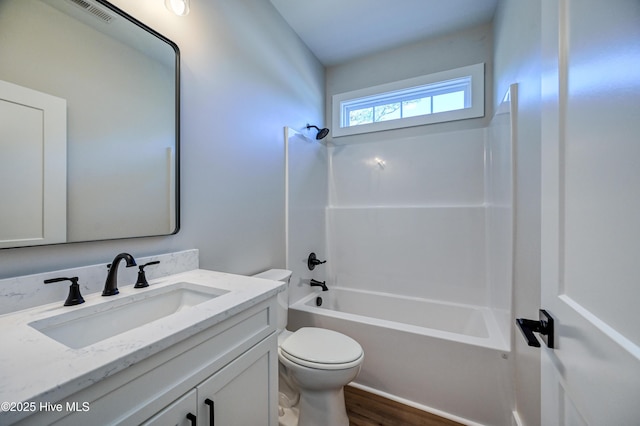 bathroom featuring wood finished floors, vanity, washtub / shower combination, toilet, and visible vents