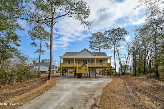 view of front of property featuring stairs, concrete driveway, a carport, a porch, and roof with shingles