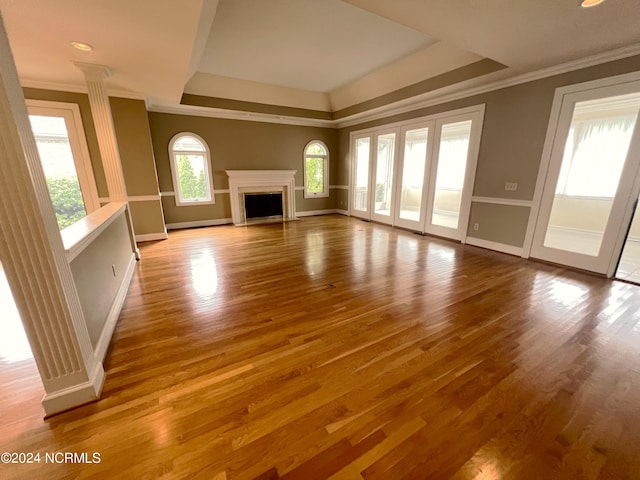 unfurnished living room featuring wood-type flooring, crown molding, and a tray ceiling