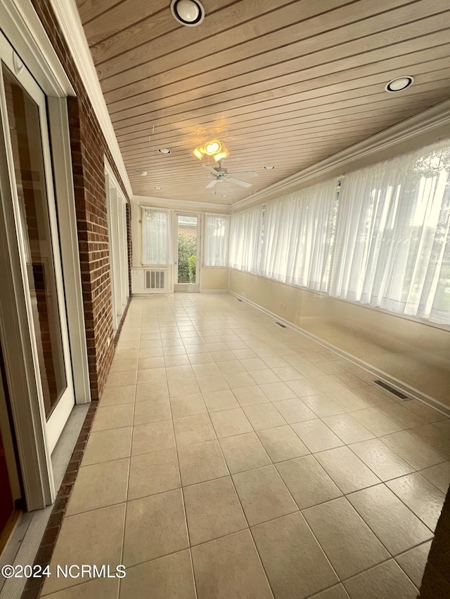 tiled empty room with crown molding, brick wall, wooden ceiling, and ceiling fan