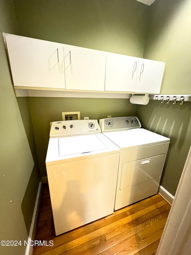 laundry area featuring cabinets, hardwood / wood-style flooring, and washer and dryer