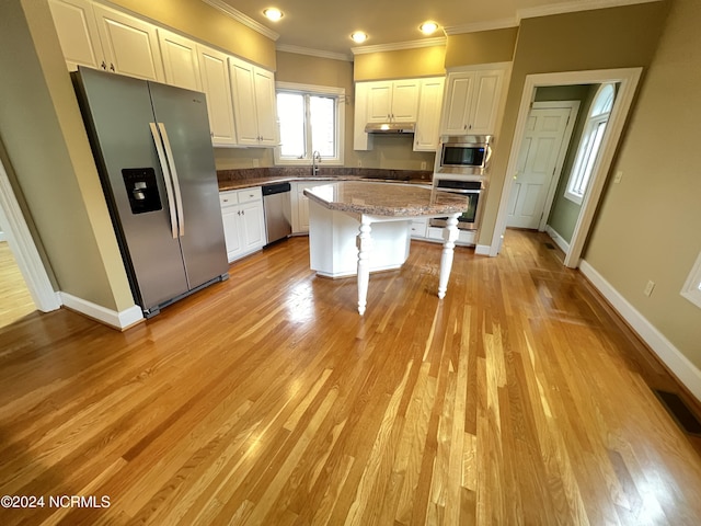 kitchen with stainless steel appliances, a center island, white cabinets, and a breakfast bar