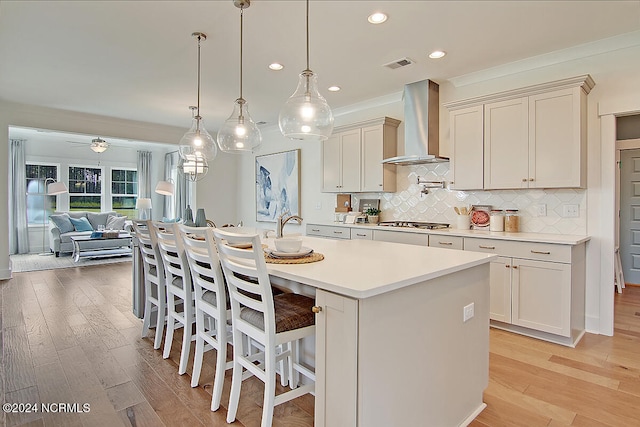 1024 Peace St Lot 73, Leland, NC 28451 - kitchen with wall chimney range hood, stainless steel gas stovetop, light countertops, a kitchen bar, and decorative backsplash