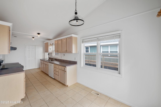 kitchen with vaulted ceiling, light brown cabinetry, decorative light fixtures, sink, and stove