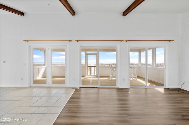 unfurnished living room featuring beam ceiling and light hardwood / wood-style flooring