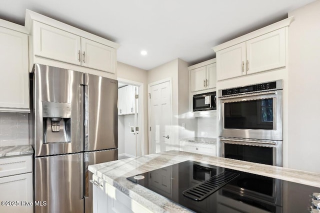 kitchen featuring white cabinetry, light stone countertops, backsplash, and stainless steel appliances