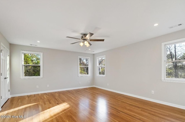 empty room with a wealth of natural light, ceiling fan, and light hardwood / wood-style flooring