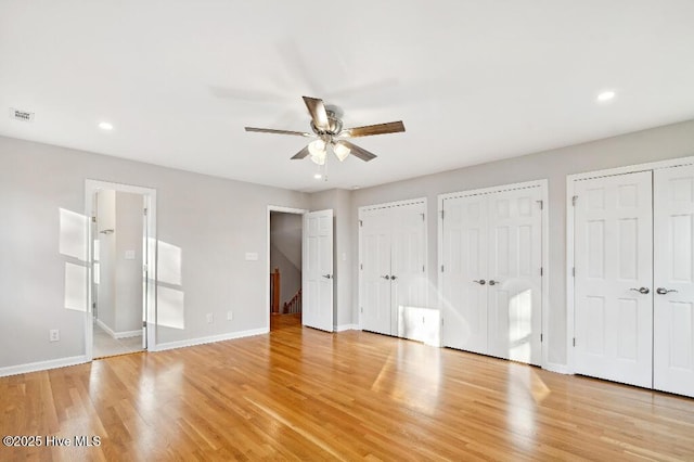 unfurnished bedroom featuring multiple closets, ceiling fan, and light hardwood / wood-style floors