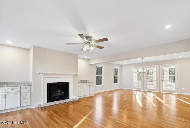 unfurnished living room featuring ceiling fan, a fireplace, and light hardwood / wood-style flooring