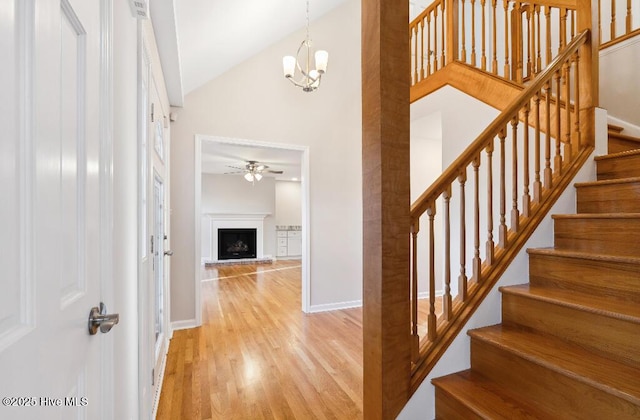 staircase featuring hardwood / wood-style flooring, high vaulted ceiling, and ceiling fan