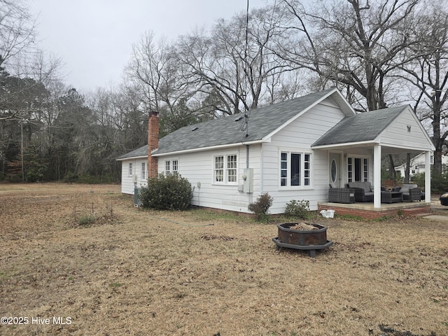 rear view of house with a fire pit, a lawn, and a patio area