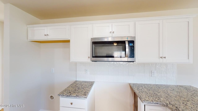 kitchen featuring white cabinetry, light stone counters, and decorative backsplash
