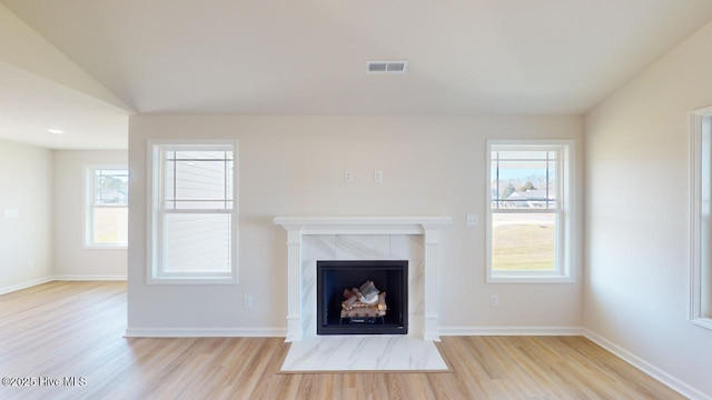 unfurnished living room with a tile fireplace, lofted ceiling, and light hardwood / wood-style floors