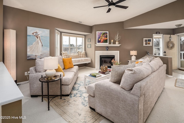 carpeted living room featuring vaulted ceiling, a tile fireplace, and ceiling fan