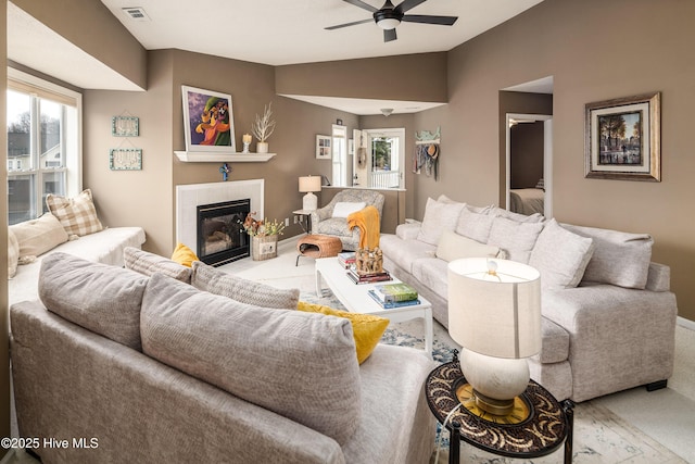 carpeted living room with ceiling fan, vaulted ceiling, a tile fireplace, and a wealth of natural light