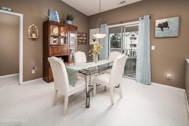 dining room with lofted ceiling and light carpet