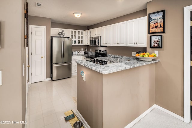 kitchen featuring light stone counters, stainless steel appliances, kitchen peninsula, and white cabinets