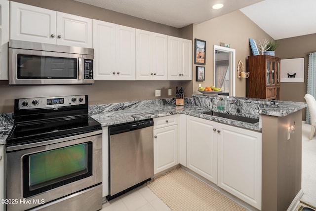 kitchen featuring sink, white cabinetry, appliances with stainless steel finishes, kitchen peninsula, and dark stone counters