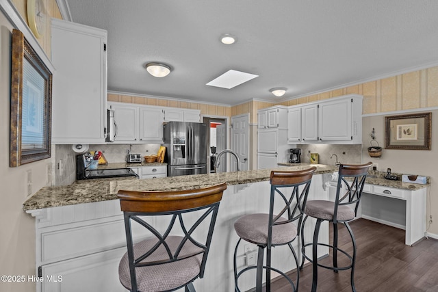 kitchen with white cabinets, decorative backsplash, appliances with stainless steel finishes, ornamental molding, and light stone countertops