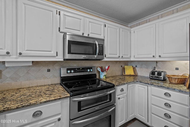 kitchen with white cabinetry, appliances with stainless steel finishes, and dark stone countertops