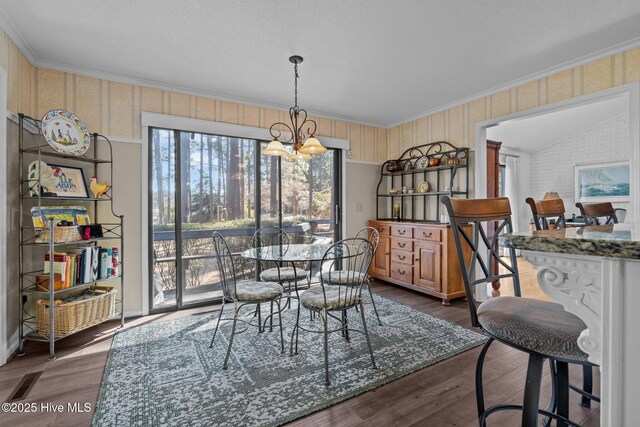 dining area featuring an inviting chandelier, crown molding, vaulted ceiling, and dark wood-type flooring