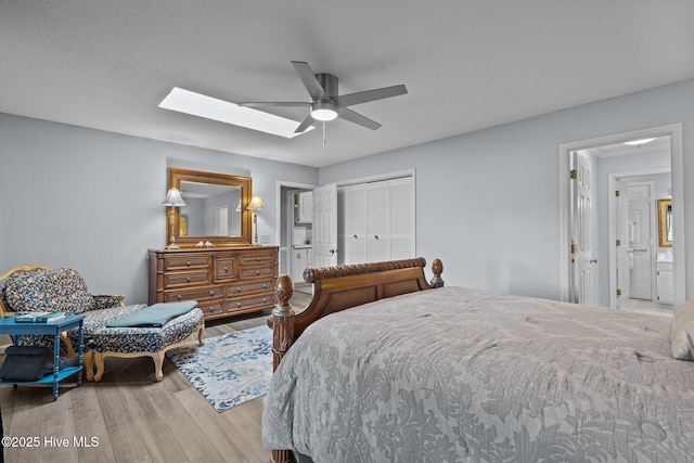 bedroom with ceiling fan, a closet, a skylight, and wood finished floors