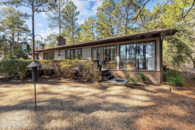 view of front of home featuring a chimney and brick siding