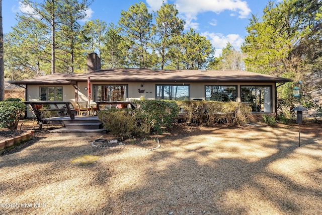 rear view of house with a chimney, a deck, and brick siding