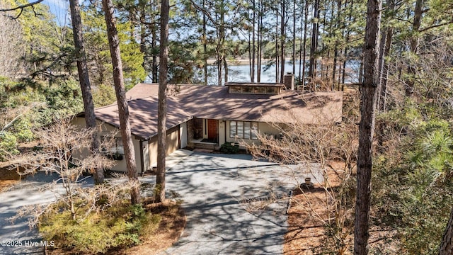 view of front of house with a water view, a garage, a chimney, and aphalt driveway