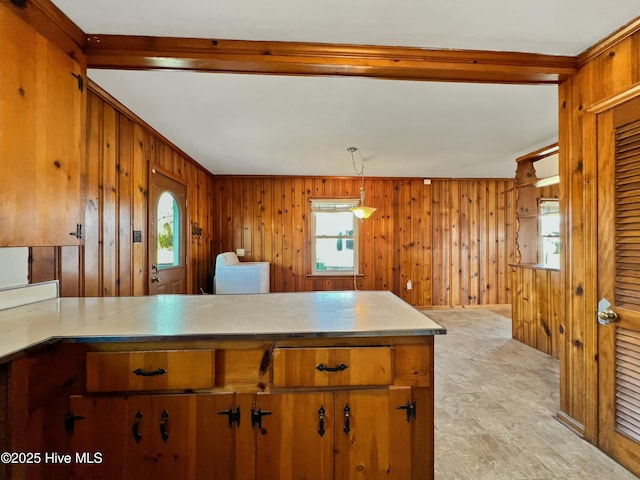 kitchen featuring a peninsula, washer / dryer, wooden walls, and brown cabinets