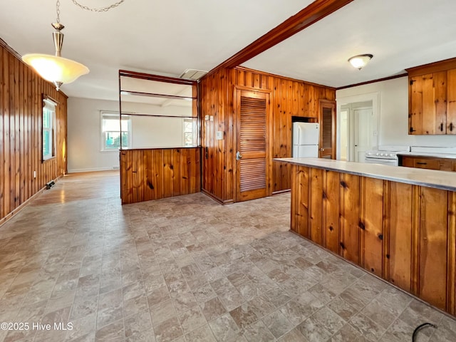 kitchen featuring white appliances, wooden walls, brown cabinets, hanging light fixtures, and light countertops