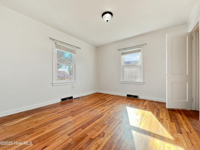 spare room featuring visible vents, light wood-style flooring, and baseboards