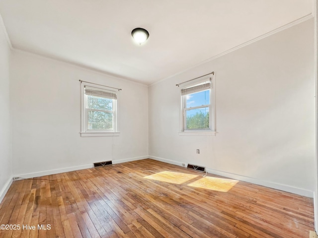 unfurnished room featuring hardwood / wood-style flooring, baseboards, visible vents, and ornamental molding