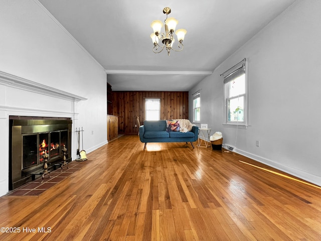 unfurnished living room with a chandelier, wood-type flooring, baseboards, a tiled fireplace, and crown molding