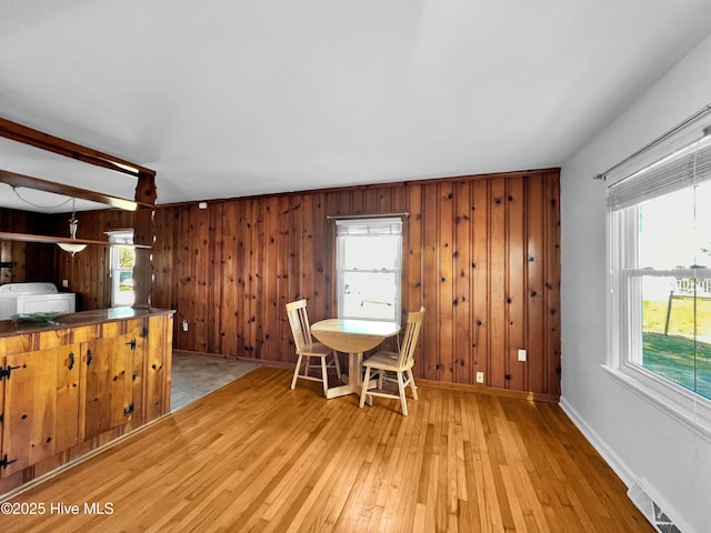 unfurnished dining area with light wood finished floors, wood walls, visible vents, and baseboards