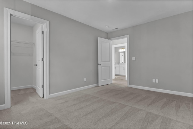 unfurnished bedroom with a closet, a spacious closet, and light carpet